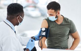 photo of a doctor examining a young man with a blood pressure gauge