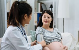 photo of doctor taking blood pressure and pregnant woman