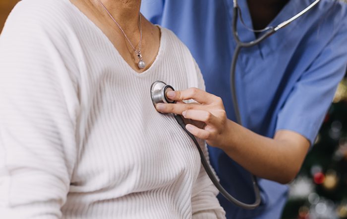 Close-up of clinician with stethoscope listening to patient's heart