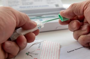 Photo of a person putting the colorectal cancer test sample in the sample holder before sending it off by mail for testing.