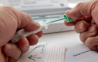 Photo of a person putting the colorectal cancer test sample in the sample holder before sending it off by mail for testing.